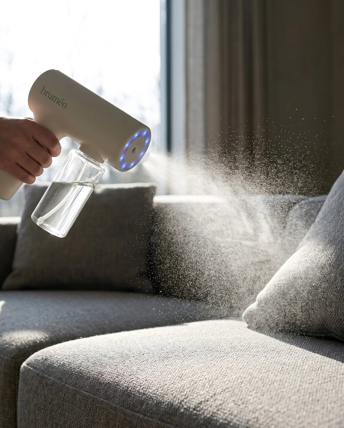 Brume ultra-fine Bruméo se déposant sur un coussin de canapé en contre-jour